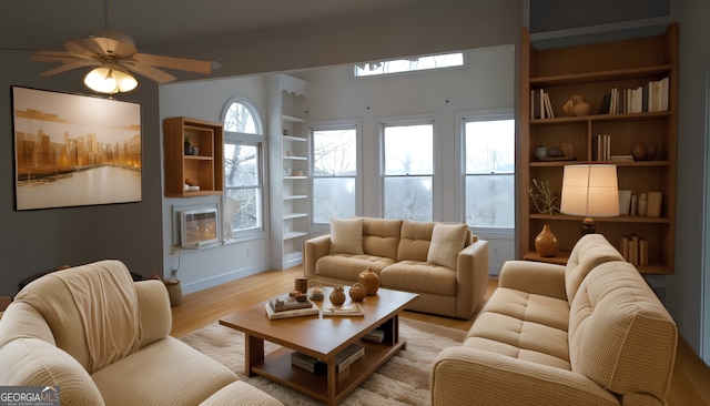 living room featuring built in shelves, ceiling fan, plenty of natural light, and light wood-type flooring