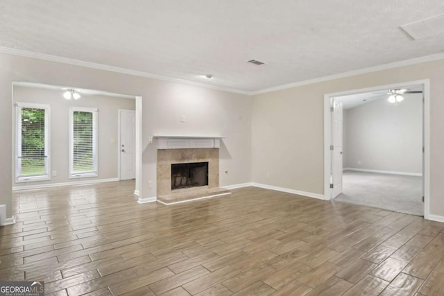 unfurnished living room with ceiling fan, crown molding, and a tiled fireplace