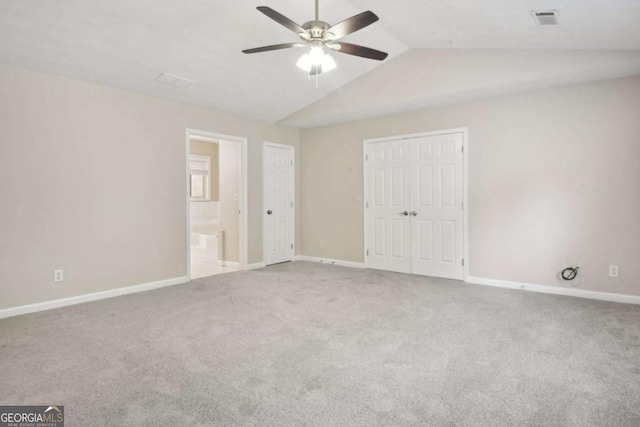 unfurnished bedroom with ensuite bath, ceiling fan, light colored carpet, and vaulted ceiling