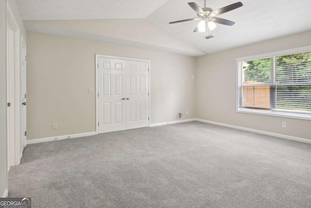 unfurnished bedroom with carpet, ceiling fan, a closet, and vaulted ceiling