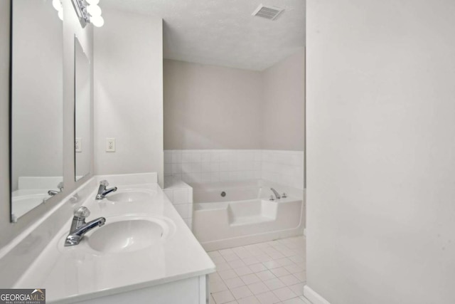 bathroom with a washtub, a textured ceiling, vanity, and tile patterned floors