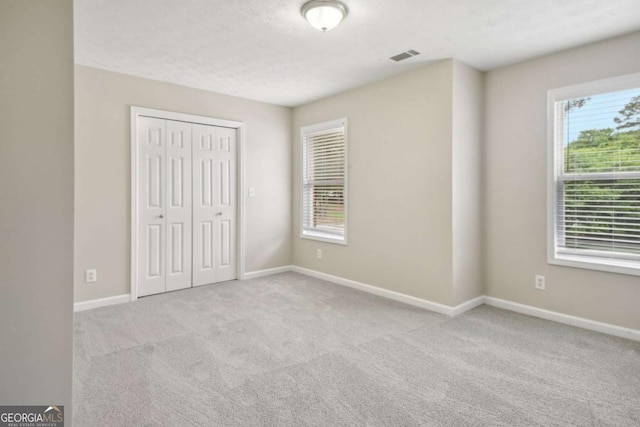 unfurnished bedroom featuring light carpet and a closet