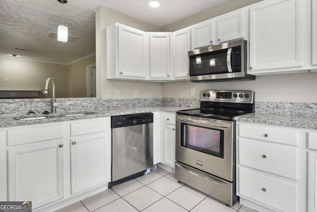 kitchen featuring sink, light tile patterned floors, ornamental molding, appliances with stainless steel finishes, and white cabinetry