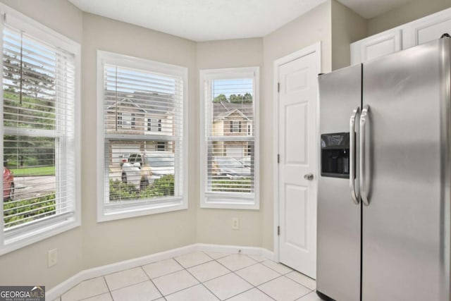 kitchen with white cabinets, light tile patterned flooring, and stainless steel refrigerator with ice dispenser