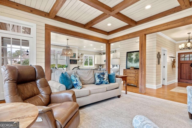 living room with wooden walls, beamed ceiling, a chandelier, and coffered ceiling