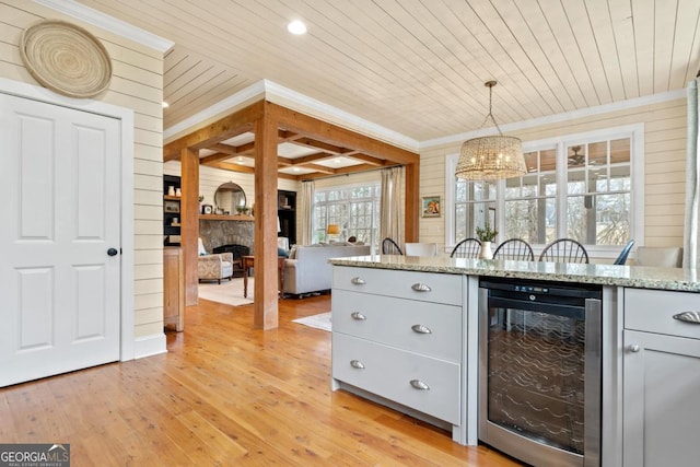 kitchen featuring pendant lighting, wood walls, wooden ceiling, wine cooler, and light wood-type flooring