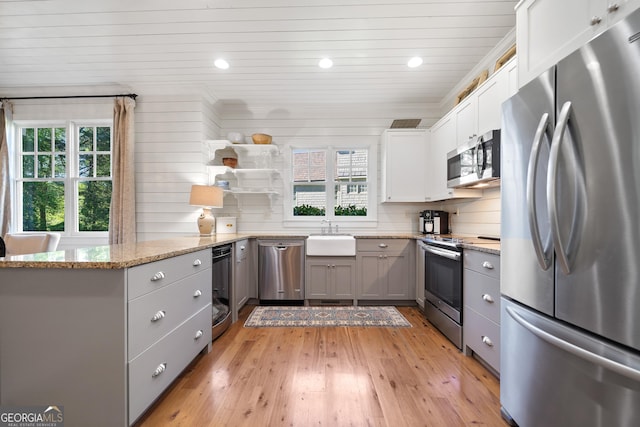 kitchen with light wood-type flooring, stainless steel appliances, gray cabinetry, and a wealth of natural light