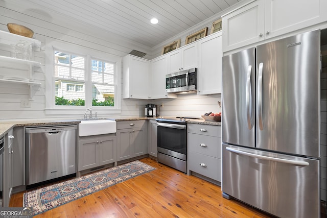 kitchen featuring light wood-style flooring, a sink, recessed lighting, gray cabinets, and appliances with stainless steel finishes
