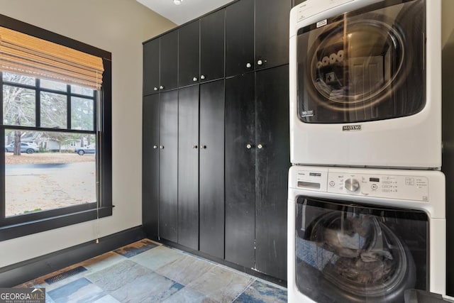 laundry area with cabinets and stacked washer and dryer