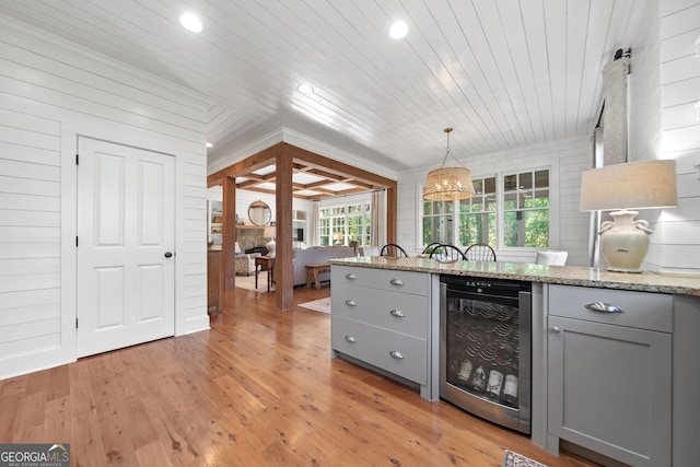 interior space featuring gray cabinets, beverage cooler, hanging light fixtures, and light wood-style floors