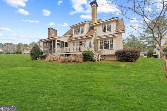 rear view of property featuring a sunroom, a wooden deck, and a lawn