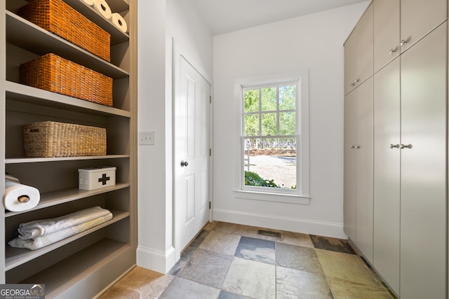 interior space with stone finish floor, visible vents, built in shelves, and baseboards