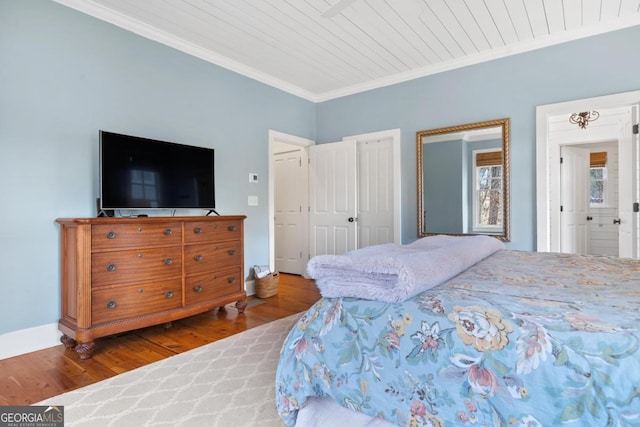 bedroom featuring wood ceiling, baseboards, wood finished floors, and crown molding