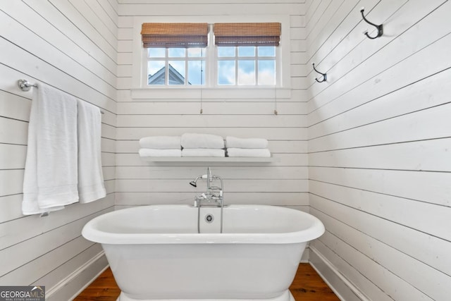 bathroom featuring a tub, wooden walls, and hardwood / wood-style flooring