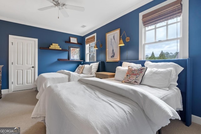 carpeted bedroom with ceiling fan, baseboards, ornamental molding, and visible vents
