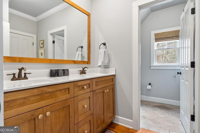 full bath with double vanity, baseboards, a sink, and ornamental molding
