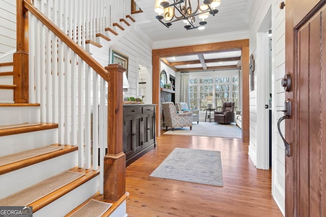 foyer featuring beamed ceiling, an inviting chandelier, light hardwood / wood-style flooring, and coffered ceiling