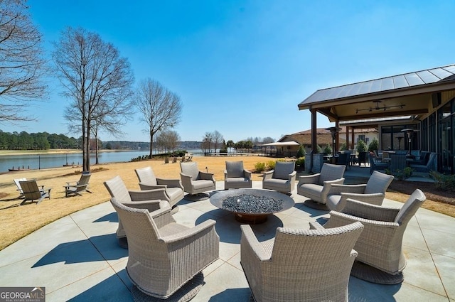 view of patio with ceiling fan, a water view, and an outdoor fire pit