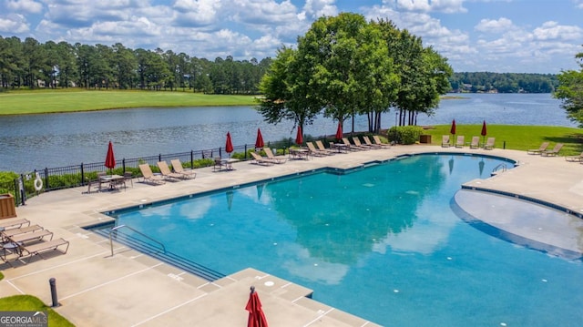pool with fence, a patio area, and a water view