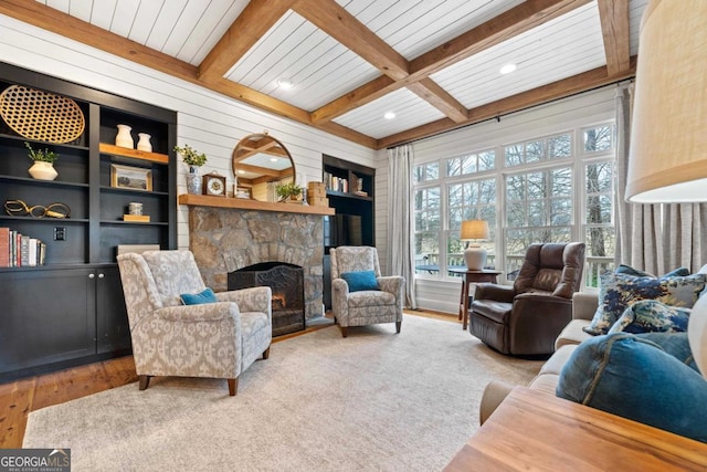 living room featuring coffered ceiling, beam ceiling, hardwood / wood-style flooring, built in features, and a stone fireplace