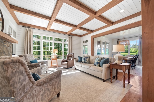 living room with a wealth of natural light, beam ceiling, a chandelier, coffered ceiling, and wood finished floors
