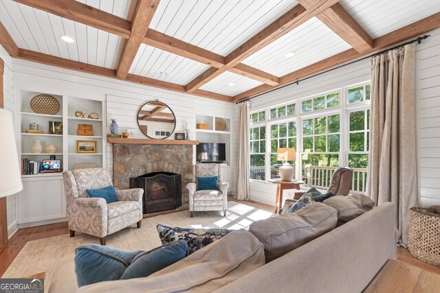 living room featuring hardwood / wood-style floors, coffered ceiling, wooden walls, a fireplace, and built in shelves