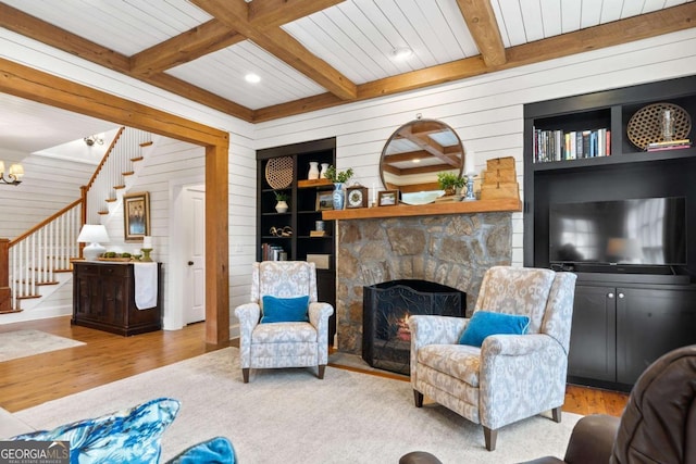 living room featuring beam ceiling, wood walls, built in features, and a fireplace