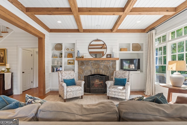 living area featuring wood finished floors, wood walls, built in shelves, and a stone fireplace