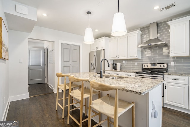 kitchen featuring white cabinetry, a center island with sink, wall chimney exhaust hood, and appliances with stainless steel finishes