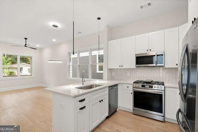 kitchen with white cabinets, decorative light fixtures, sink, and appliances with stainless steel finishes