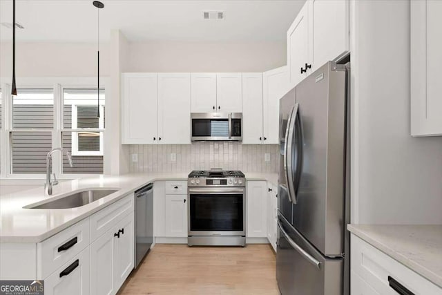 kitchen featuring white cabinets, decorative light fixtures, sink, and stainless steel appliances