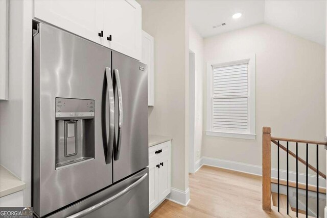 kitchen featuring white cabinets, stainless steel fridge, lofted ceiling, and light hardwood / wood-style floors