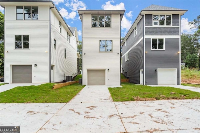 view of front of property with a front lawn, cooling unit, and a garage