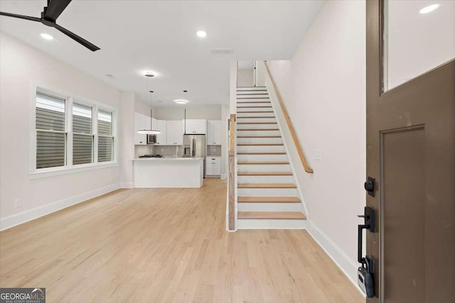 unfurnished living room with ceiling fan and light wood-type flooring