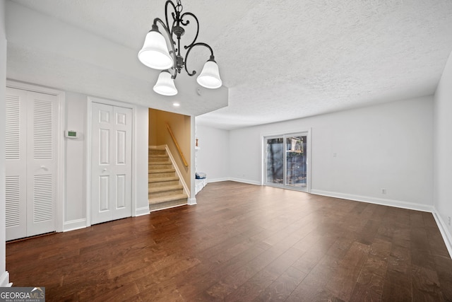 unfurnished living room with dark wood-type flooring and a textured ceiling