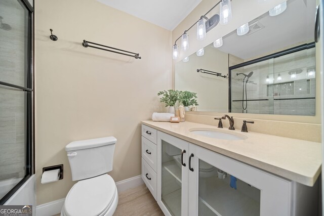 bathroom featuring vanity, toilet, and an enclosed shower