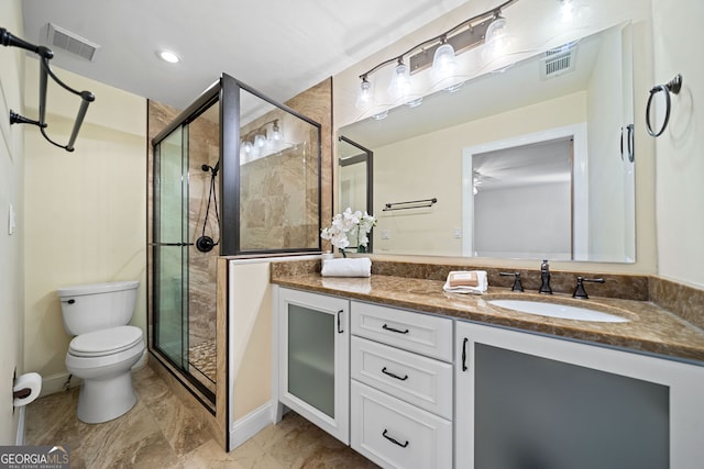 bathroom featuring a shower with door, vanity, and toilet