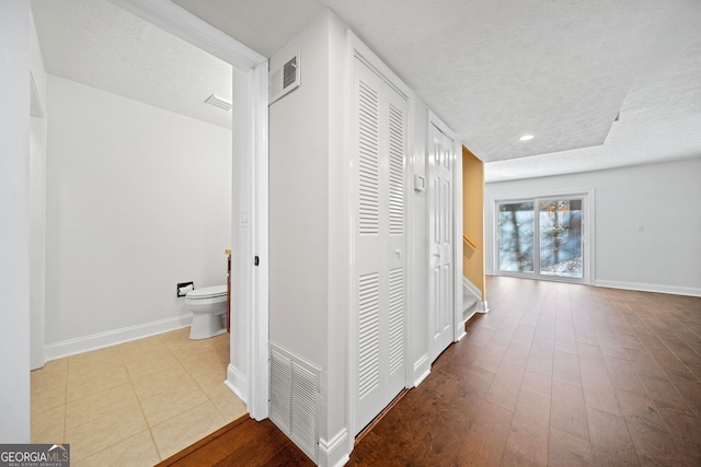 hallway with a textured ceiling and light hardwood / wood-style floors