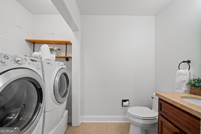 laundry area with independent washer and dryer, a textured ceiling, and light tile patterned floors