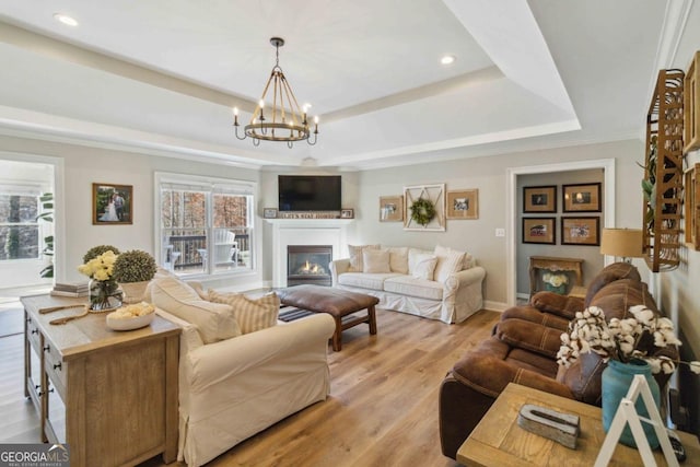 living room with light hardwood / wood-style floors, a tray ceiling, and a chandelier