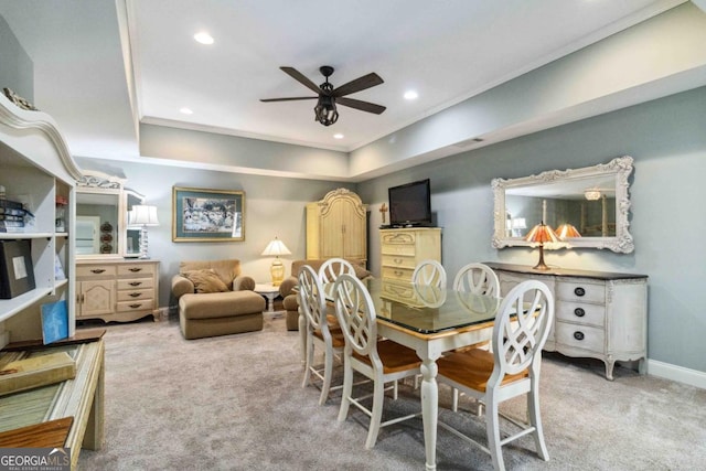 dining space featuring ornamental molding, ceiling fan, light colored carpet, and a tray ceiling