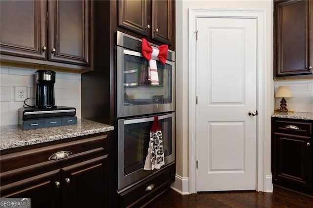 kitchen featuring dark hardwood / wood-style floors, decorative backsplash, double oven, dark brown cabinets, and light stone counters