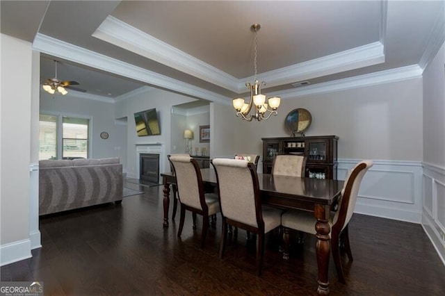 dining space featuring ceiling fan with notable chandelier, dark hardwood / wood-style flooring, a raised ceiling, and ornamental molding