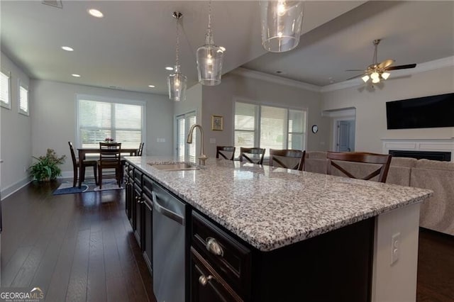 kitchen featuring sink, stainless steel dishwasher, an island with sink, pendant lighting, and ornamental molding