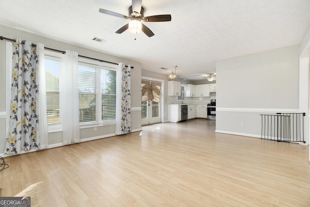 unfurnished living room with ceiling fan, sink, a textured ceiling, and light wood-type flooring