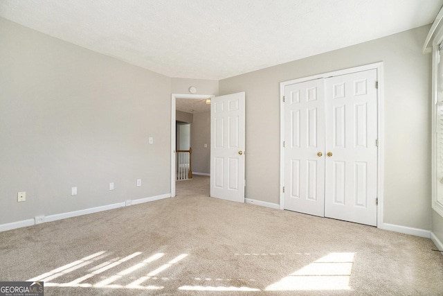 unfurnished bedroom featuring light carpet and a closet