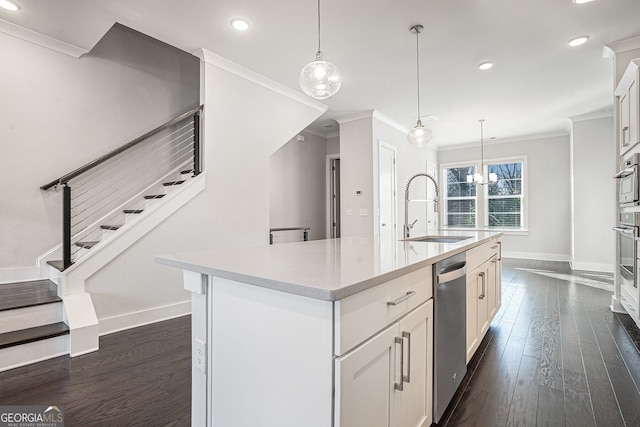 kitchen featuring ornamental molding, sink, decorative light fixtures, white cabinets, and an island with sink