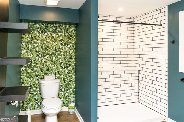 bathroom with hardwood / wood-style floors, toilet, and a tile shower