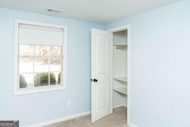 unfurnished bedroom with light carpet and a closet