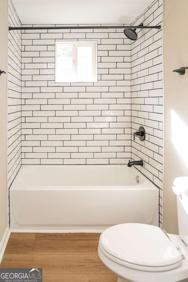 bathroom featuring toilet, tiled shower / bath combo, and hardwood / wood-style floors